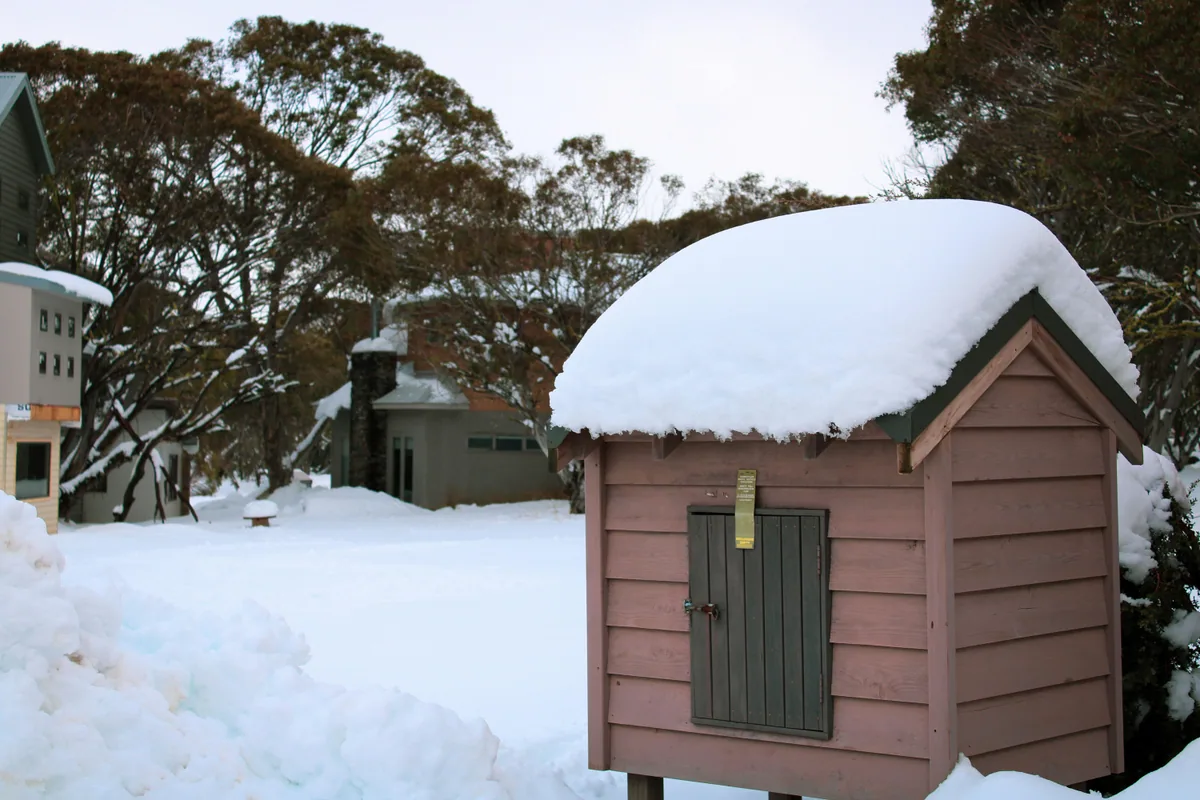 A small shed or dog box covered in snow at Dinner Plain.
